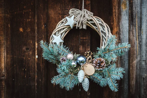 Vánoční věnec na rustikální dřevěné dveře pozadí modrého stromu. — Stock fotografie