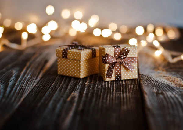 Kerstpakket doos lag op een houten tafel op een achtergrond bokeh van feestelijke verlichting. — Stockfoto