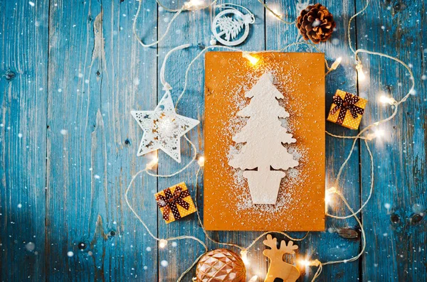 Decoraciones de año nuevo alrededor de la carta de Navidad espacio vacío para el texto quemando guirnaldas luces sobre fondo de madera azul. — Foto de Stock