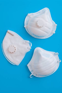 Mavi arka planda beyaz maske solunum cihazı. Yüz maskesi çevre kirliliğine, grip virüslerine ve koronavirüse karşı korur. Sağlık ve Cerrahi Konsept.