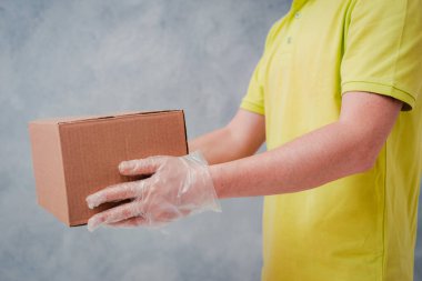 Kurye, tek kullanımlık eldivenlerde karton kutular tutuyor. Koronavirüs için karantina döneminde temas kurulamadı..