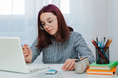 Kız öğrenci ev ödevi yapıyor. Ev ödevi yapıyor. Müzik dinliyor. Kulaklık takıyor, uzaktan iletişim kuruyor.