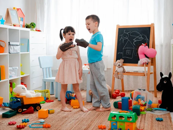 男の子と女の子の子供たちは騒々しいおもちゃの恐竜を叫び 子供部屋で楽しんでいます ゲーム中の子供の自己表現と感情 いたずら 兄弟姉妹 — ストック写真