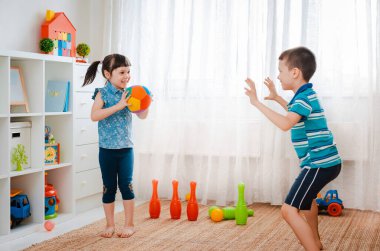 Yerli bir çocukla bir kız oyun odasında top oynuyorlar. Etkileşim konsepti, kardeşlik, iletişim, karşılıklı oyun, karantina, kendini tecrit evi, kardeş kardeş.