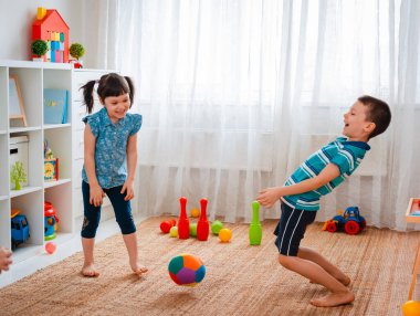 Yerli bir çocukla bir kız oyun odasında top oynuyorlar. Etkileşim konsepti, kardeşlik, iletişim, karşılıklı oyun, karantina, kendini tecrit evi, kardeş kardeş.