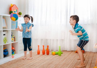 Yerli bir çocukla bir kız oyun odasında top oynuyorlar. Etkileşim konsepti, kardeşlik, iletişim, karşılıklı oyun, karantina, kendini tecrit evi, kardeş kardeş.