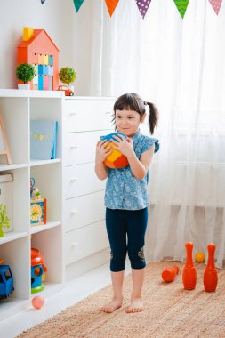 Çocuklar oyun odasında top oynayan küçük bir kız çocuğu. etkileşim konsepti ebeveyn ve çocuk, iletişim, karşılıklı oyun, karantina, kişisel izolasyon evi, eğitim.