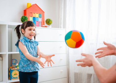 Çocuklar oyun odasında top oynayan küçük bir kız çocuğu. etkileşim konsepti ebeveyn ve çocuk, iletişim, karşılıklı oyun, karantina, kişisel izolasyon evi, eğitim.