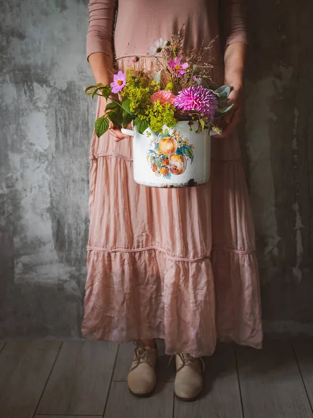 Mujer con estilo florista profesional mantiene composición flores silvestres maceta Floristería Fondo, hormigón, pared gris . — Foto de Stock