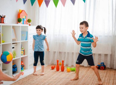 Yerli bir çocukla bir kız oyun odasında top oynuyorlar. Etkileşim konsepti, kardeşlik, iletişim, karşılıklı oyun, karantina, kendini tecrit evi, kardeş kardeş.