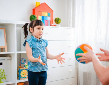 Çocuklar oyun odasında top oynayan küçük bir kız çocuğu. etkileşim konsepti ebeveyn ve çocuk, iletişim, karşılıklı oyun, karantina, kişisel izolasyon evi, eğitim.