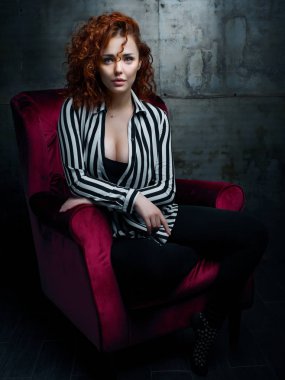 Kıvırcık kadın kırmızı koltuğa siting