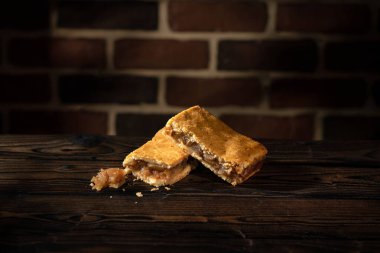 Ahşap masada iki elmalı pasta ve tuğla duvar arkaplanı