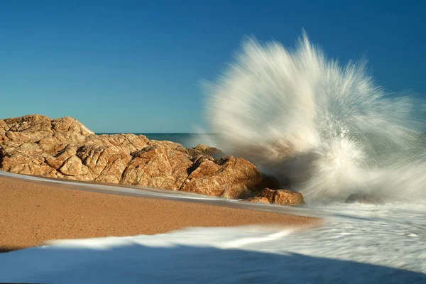 The waves breaking on a stony beach, forming a spray. — Stock Photo, Image