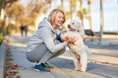 Yaşlı bir kadın dışarıda köpekle yürüyor..