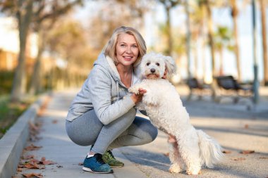 Yaşlı bir kadın dışarıda köpekle yürüyor..