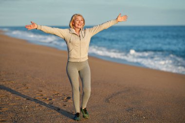 Happy elderly sports woman walks by the sea.