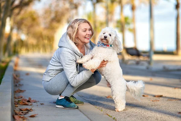 Ältere Frau spaziert mit Hund im Freien. — Stockfoto