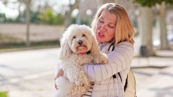 Medelålders kvinna promenader med fluffig vit hund i sommar stad — Stockvideo