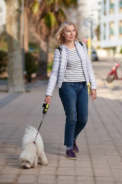 夏城带着毛茸茸的白狗散步的迷人中年妇女 — 图库照片