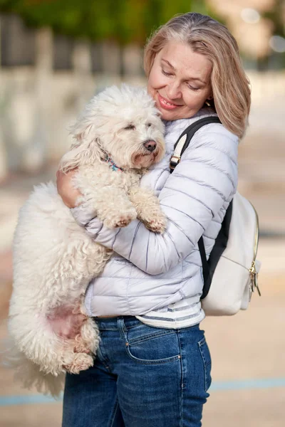 Mulher de meia-idade andando com cachorro branco fofo na cidade de verão — Fotografia de Stock