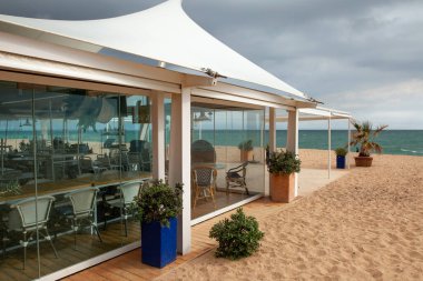 Beyaz ahşap mobilyaları ve doğal okyanus manzaralı palmiye ağaçları olan harici restoran otel yemek alanı.