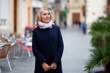 Olgun kadın turist şehrin sokaklarında yürüyor.