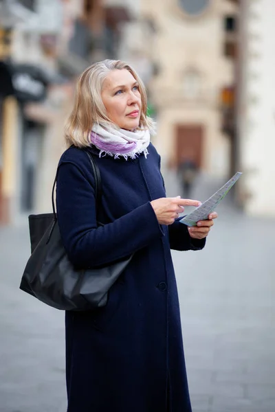 Volwassen vrouw toerist met een kaart in de hand loopt de straten van de stad — Stockfoto