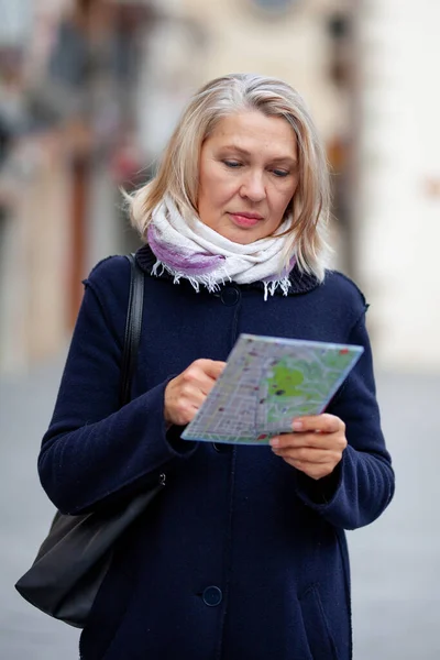 Reife Touristin mit Landkarte in der Hand spaziert durch die Straßen der Stadt — Stockfoto
