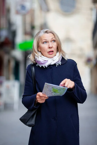 Femme touriste avec un plan en main parcourt les rues de la ville — Photo