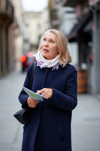 Mulher turista com um mapa na mão caminha ao longo da rua — Fotografia de Stock