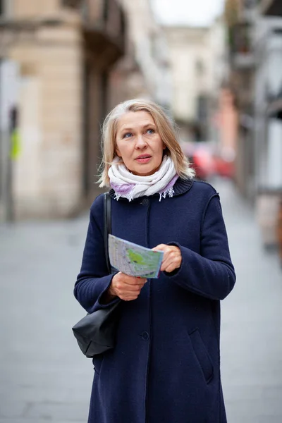 Kobieta turystka z mapą w ręku spaceruje ulicą — Zdjęcie stockowe