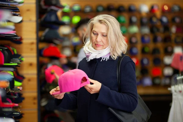 Vrouwen in hoedenwinkel kiest honkbalpet. — Stockfoto