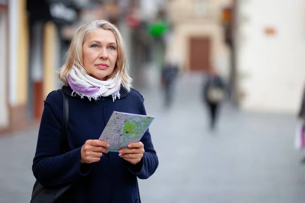 Зрелая женщина турист с картой в руке прогулки по улицам города — стоковое фото