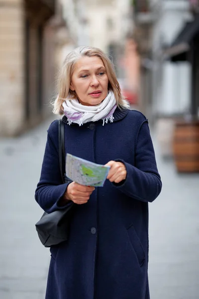 Kvinna turist med en karta i handen promenader längs gatan — Stockfoto