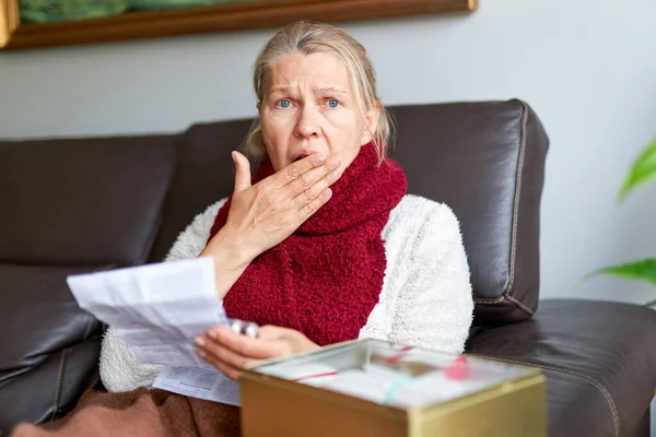 Frau nimmt Medikamente. Frau hält Blisterpackung mit Pillen in der Hand und liest medizinische Anweisungen. — Stockfoto