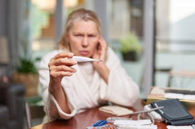 Hastalık, mevsimsel virüs problemi konsepti. Son sınıf öğrencisi kadın termometrede grip oluyor..