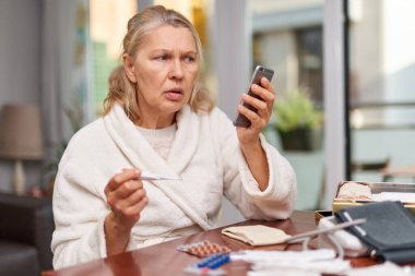 Hastalık, mevsimsel virüs problemi konsepti. Son sınıf öğrencisi kadın termometrede grip oluyor..