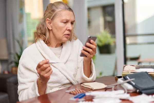 Ziekte, seizoensgebonden virus probleem concept. Oudere vrouw ziek met griep op temperatuur op thermometer. — Stockfoto