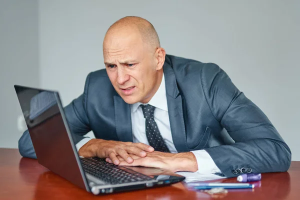 Homem de negócios frustrado trabalhando no computador portátil no escritório — Fotografia de Stock