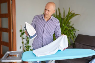 Ev işi ve ev işi - evdeki demir tahtada ütü yapan adam