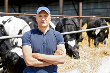 Çiftlikte bir inekle pozitif bir çiftçinin portresi.