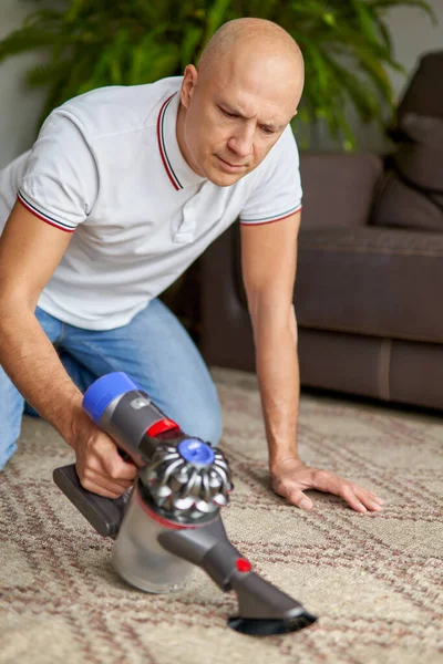 Cara usando aspirador de pó tapete de limpeza remove poeira manter limpo na sala de estar . — Fotografia de Stock