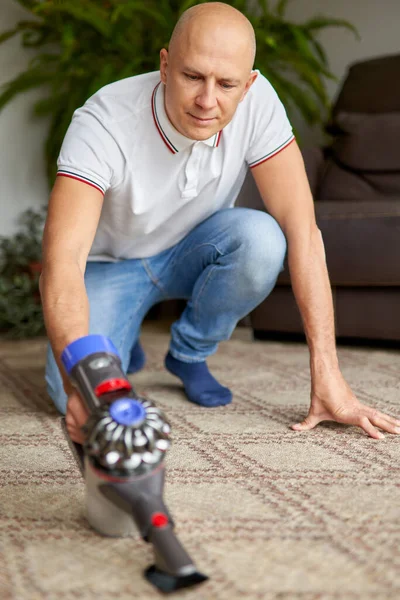 Cara usando aspirador de pó tapete de limpeza remove poeira manter limpo na sala de estar . — Fotografia de Stock