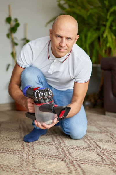 Guy met behulp van stofzuiger reinigen tapijt verwijdert stof schoon te houden in de woonkamer. — Stockfoto