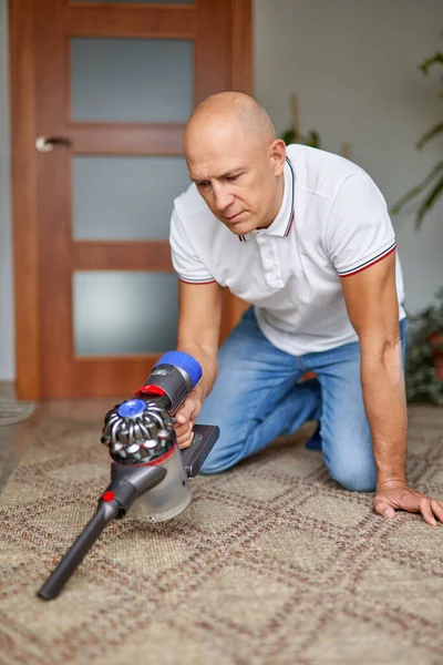 Ung man rengöring matta med vakuum i vardagsrummet. — Stockfoto