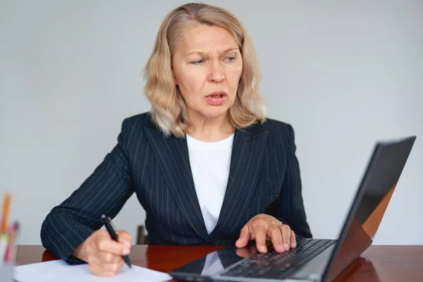 一位严肃的女商人在办公室使用笔记本电脑的肖像 — 图库照片
