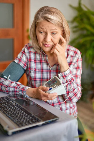 Volwassen vrouw meten van de bloeddruk door een elektronische tonometer — Stockfoto