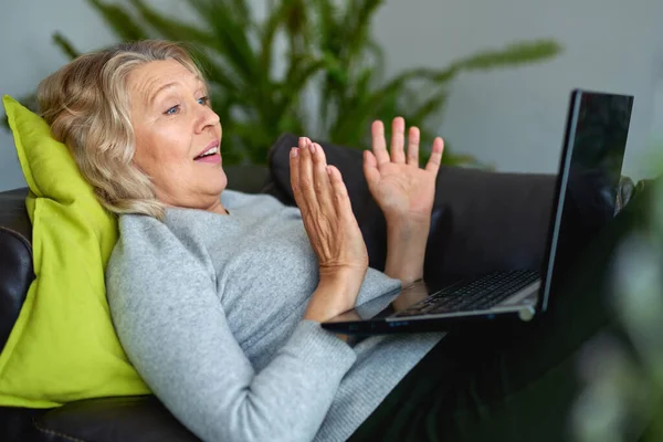 Vrouw liggend op een bank thuis met een laptop — Stockfoto