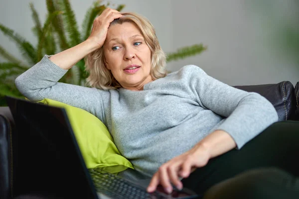 女人抱着笔记本电脑躺在家里的沙发上 — 图库照片
